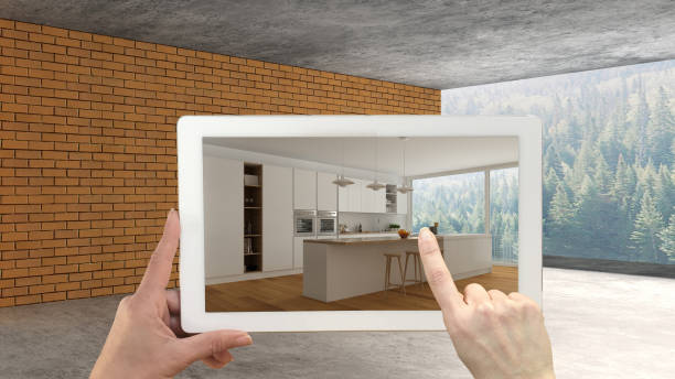 istock Augmented reality concept. Hand holding tablet with AR application used to simulate furniture and design products in an interior construction site, modern kitchen with island 1088952296