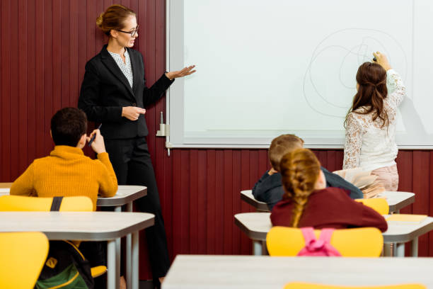 istock young teacher showing the whiteboard and schoolkid writing during presentation 1088956016