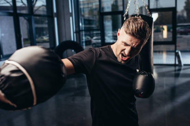 istock handsome boxer exercising with trainer and screaming in gym 1088958030