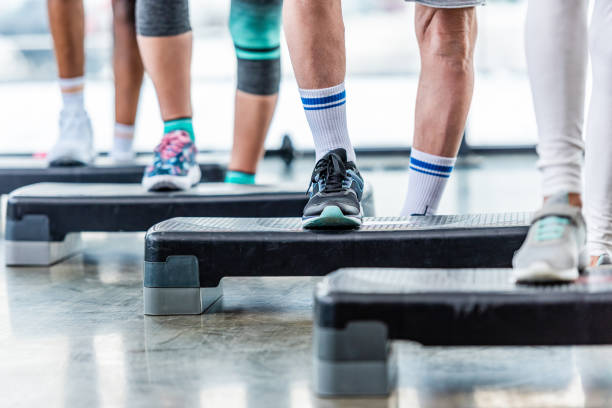 istock partial view of sportspeople doing exercise on step platforms at gym 1088958464