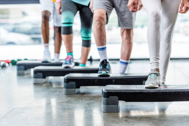 istock cropped image of sportspeople doing exercise on step platforms at gym 1088958468