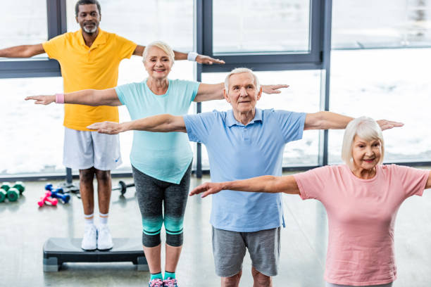 istock high angle view of multicultural senior athletes synchronous exercising on step platforms at sports hall 1088958478