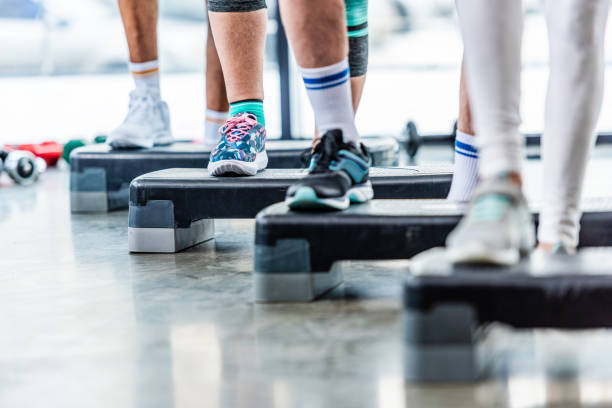 istock partial view of sportspeople doing exercise on step platforms at gym 1088958496