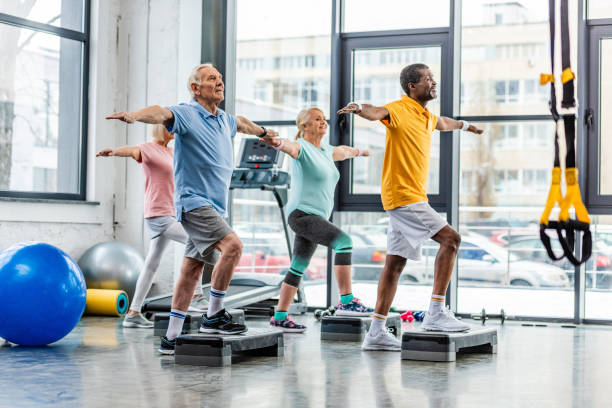 istock multicultural senior sportspeople synchronous exercising on step platforms at gym 1088958536