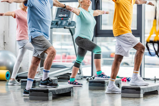istock partial view of senior athletes synchronous exercising on step platforms at gym 1088958574