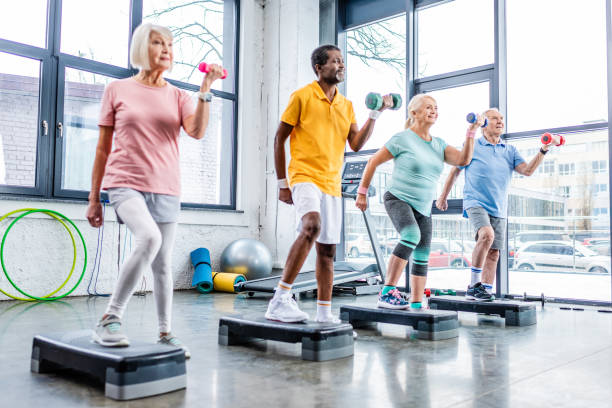 istock multicultural senior sportspeople synchronous exercising with dumbbells on step platforms at gym 1088958594