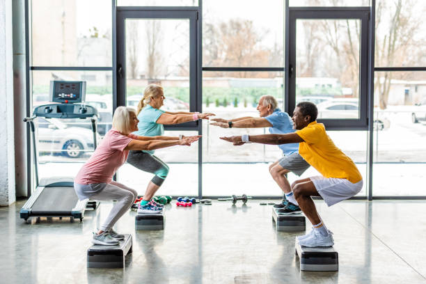 istock multicultural senior athletes synchronous doing squats on step platforms at gym 1088958646