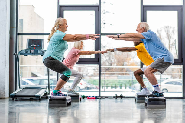 istock side view of mature athletes synchronous doing squats on step platforms at gym 1088958664