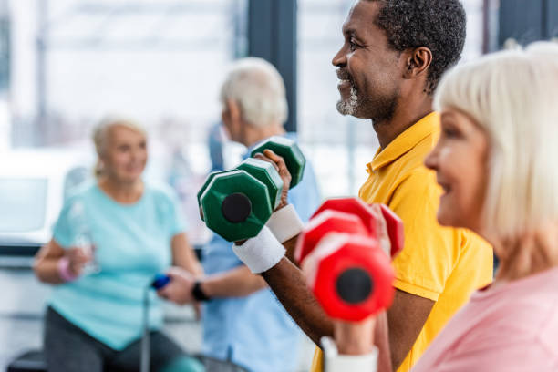 selektywne skupienie międzyrasowej dojrzałej pary wykonującej ćwiczenia z hantlami na siłowni - senior adult healthy lifestyle athleticism lifestyles zdjęcia i obrazy z banku zdjęć