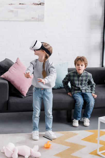 istock beautiful brother and sister using virtual reality headset at home 1088961490
