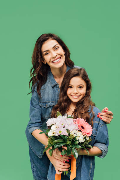 sourire de mère fille embrassant avec bouquet de fleurs isolée sur vert - mother family vertical flower photos et images de collection