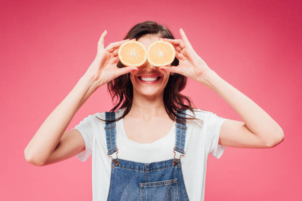 istock smiling woman holding oranges over eyes isolated on pink 1088964542