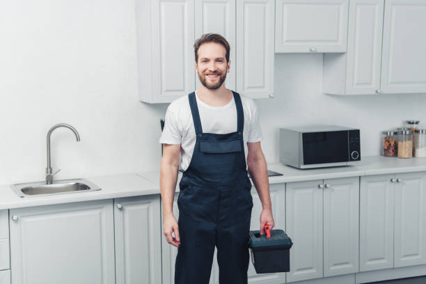 istock happy repairman in working overall holding toolbox in kitchen at home 1088964924