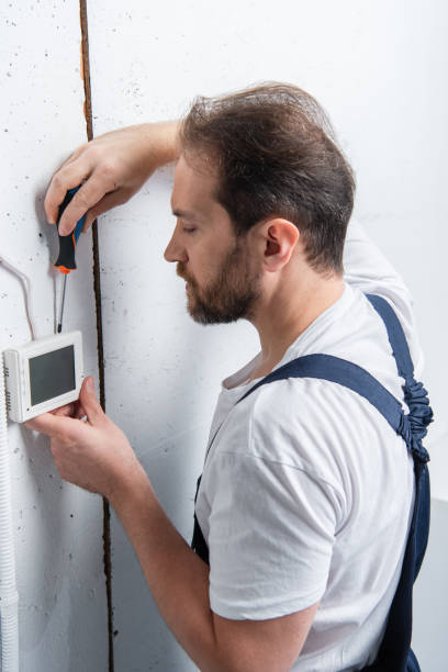 istock male electrician with clipboard fixing electrical box by screwdriver 1088965288