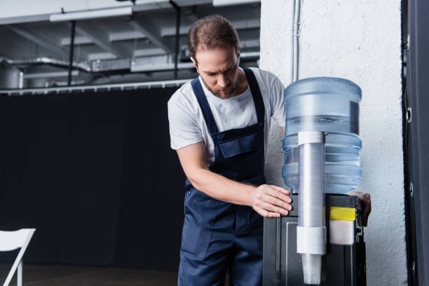 istock serious handyman in working overall checking broken water cooler 1088965506