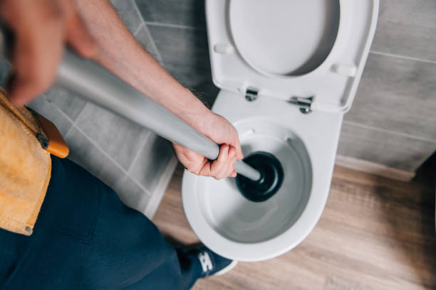 toma recortada de hombre fontanero con émbolo y limpieza de wc en cuarto de baño - plunger fotografías e imágenes de stock