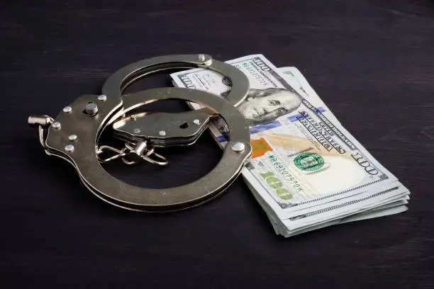 Photo of Handcuffs and money. Dollars for bail bonds.