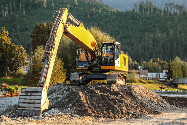 istock Yellow excavator (digger machine) digging stones, in river, forest in background 1088969668