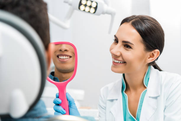 istock handsome african american man smiling while attractive dentist holding mirror 1088970456