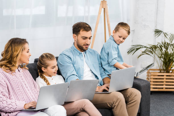 istock happy family sitting on sofa and using laptops in living room 1088970818