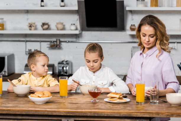 istock cute siblings with mom eating porridge at table 1088971212