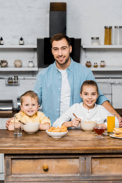 istock smiling father with siblings looking at camera at kitchen table 1088971254