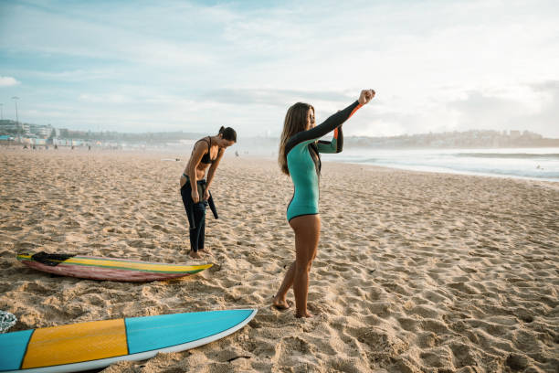 istock Two young women putting on wet suits for surfing 1088972776