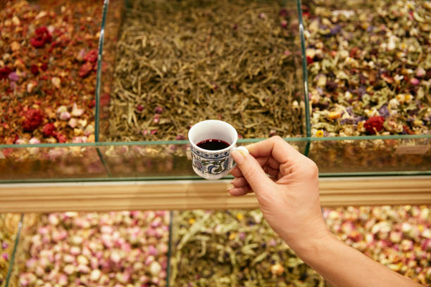Hand With Cup Of Turkish Red Tea In Store Closeup, Assortment Of Tea On Background At Market. High Resolution