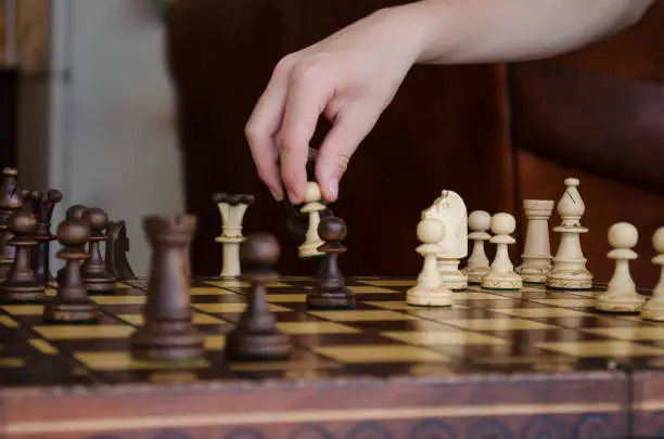 Wide cropped image of a human hand moving a chess piece of a light pawn at the table. The concept of strategy a management or leadership