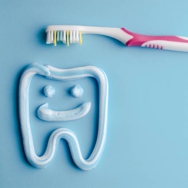 istock Toothpaste in a form of a smiling tooth with a pink toothbrushe on blue. Toothpaste on blue. Dental hygiene. 1088977254