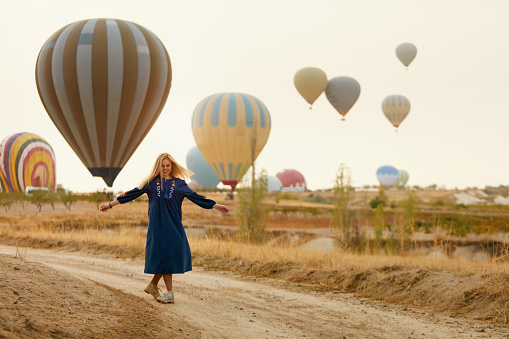 Woman Having Fun With Flying Hot Air Balloons On Background, Girl Traveling In Cappadocia. High Resolution