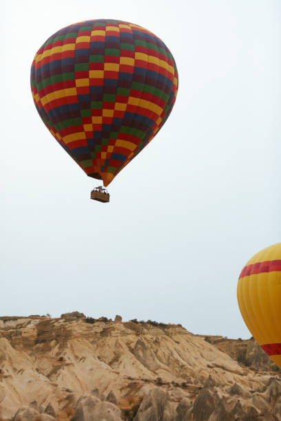 土地の上空を飛んでいるバスケットにカラフルな熱気球 - turkey hot air balloon cappadocia basket ストックフォトと画像
