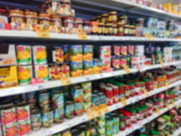 blurred abstract image. goods on the shelf of a grocery store. canned vegetables and fruit - canned food imagens e fotografias de stock