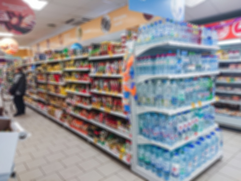 Blurred abstract image. Goods on the shelf of a grocery store. Water in plastic bottles and other goods.