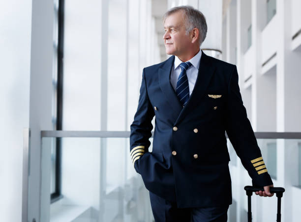 Experienced senior pilot pulling his luggage in the airport terminal