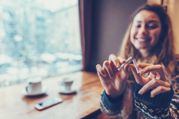 woman quitting smoking - breaking cigarette imagens e fotografias de stock