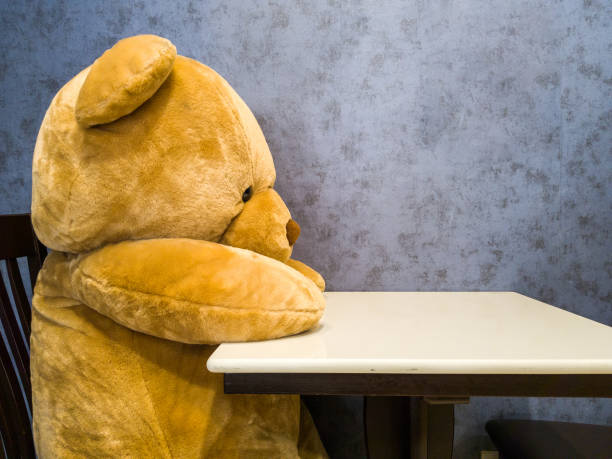 Cute teddy bear sit on the chair in front of dining table. Make it seem like waiting for favorite dish.