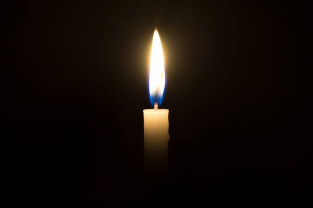 istock A single candle light glowing on a white candle in the middle part of frame on black background 1089021234