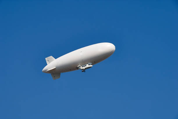 Large white dirigible airship against a clear blue sky. Plenty of room for text. Large white dirigible airship against a clear blue sky. Plenty of room for text. blimp stock pictures, royalty-free photos & images