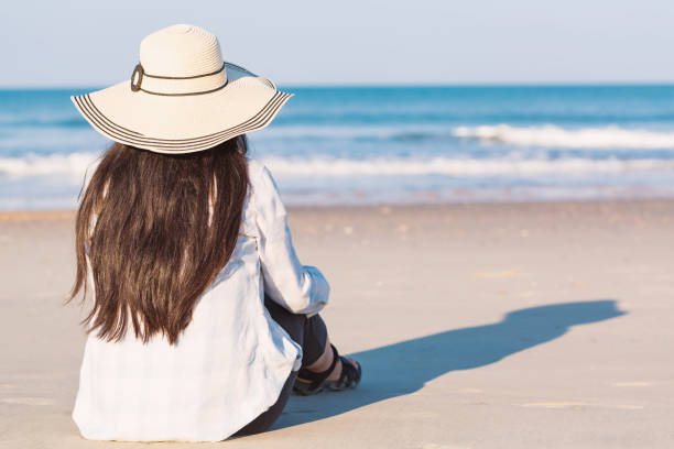 istock Woman in a hat sitting on the beach 1089035820