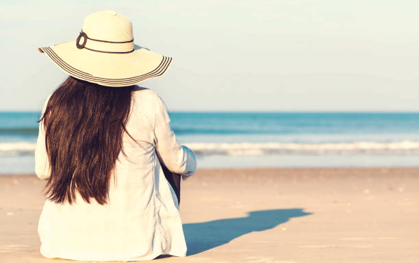 istock Woman in a hat sitting on the beach 1089035832