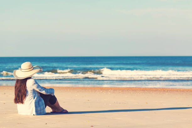 istock Woman in a hat sitting on the beach 1089035834