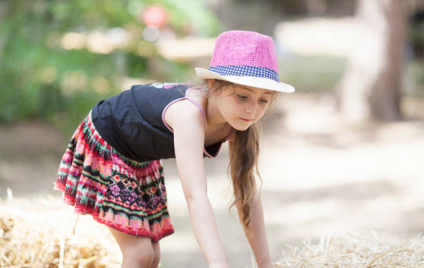 istock Little girl in straw hat playing with hay 1089035878