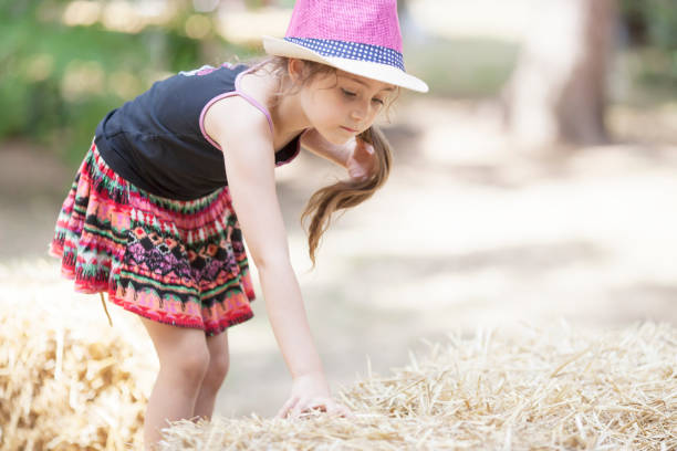 istock Little girl in straw hat playing with hay 1089036184