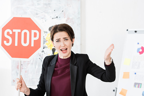 angry businesswoman holding stop sign and screaming in office
