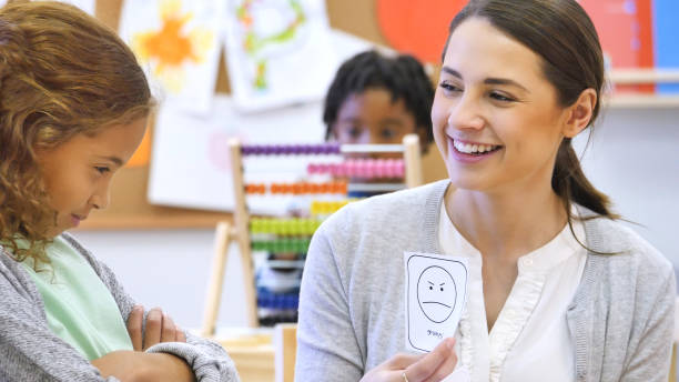 istock Young, female teacher smiles at student while holding flashcard 1089056080