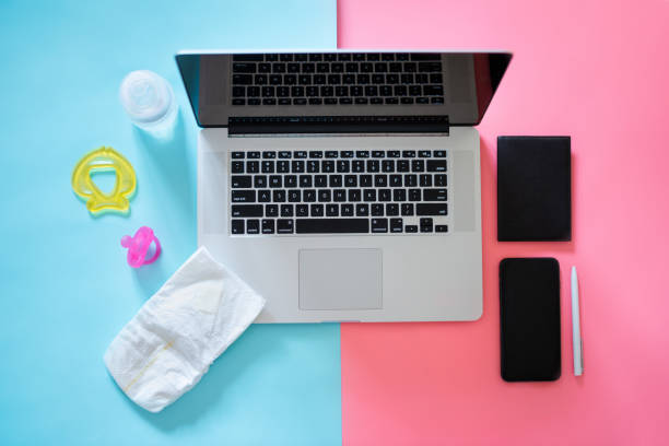 Working mom top view flatlay of workplace baby items and laptop with phone stock photo