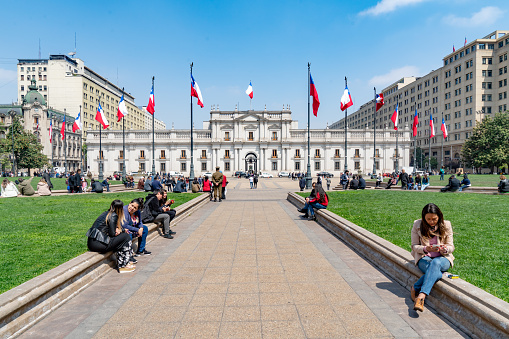Santiago, Chile - October 12, 2018: La Moneda Palace,   Construction began in 1784 and was opened in 1805. People are visiting and resting in the square.