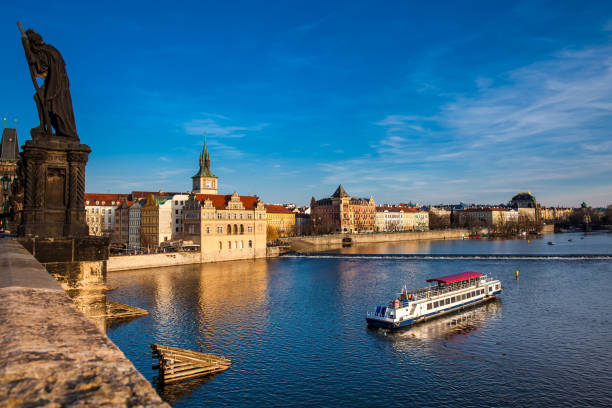 Boat navigating on Vltava river at sunset in Prague