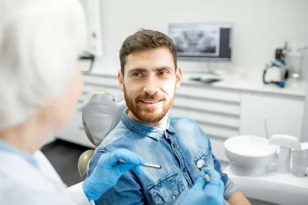 Handsome man during the dental consultation with elderly woman dentist in the dental office